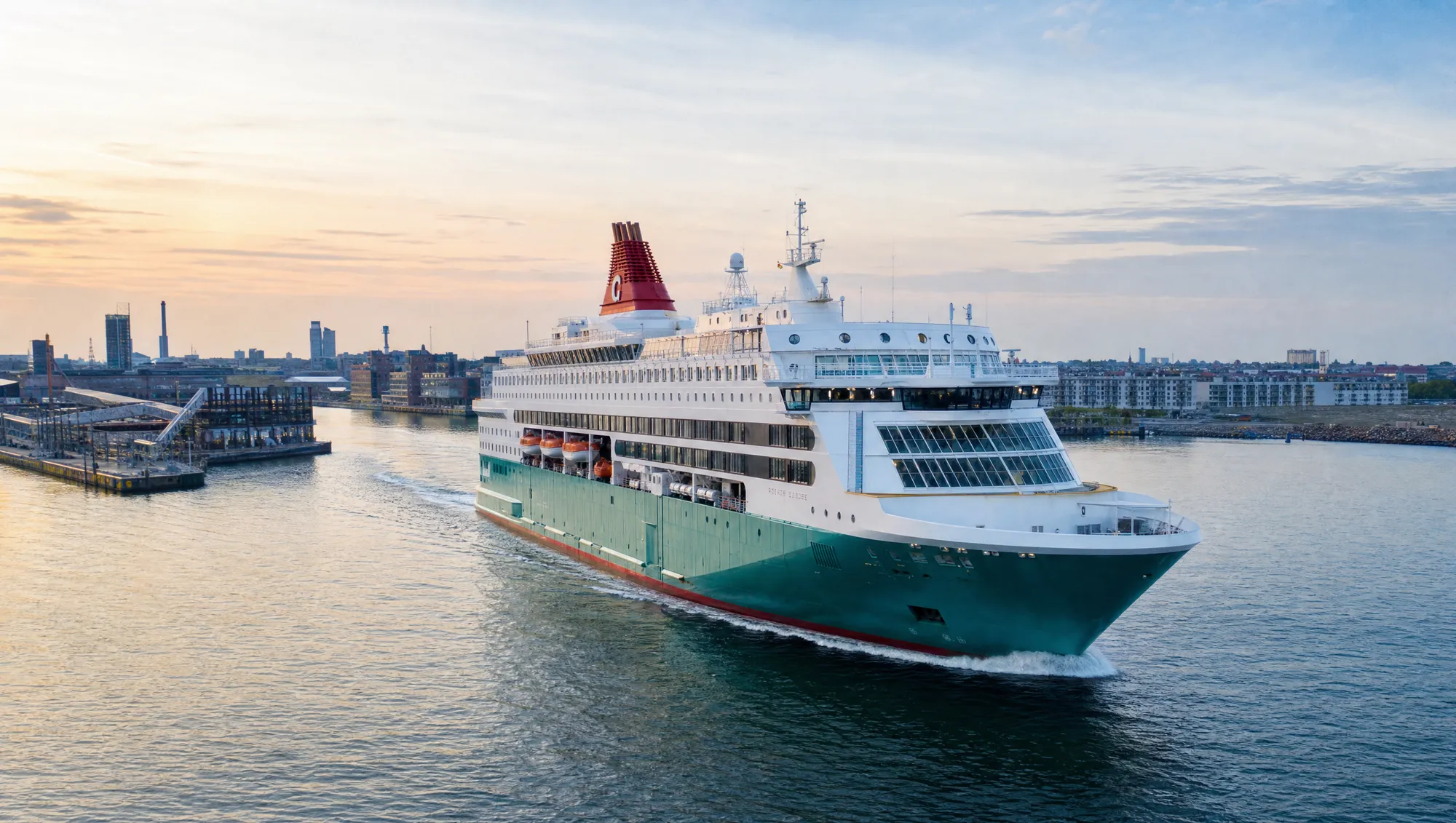 A ferry with a green hull sailing into port at sunset
